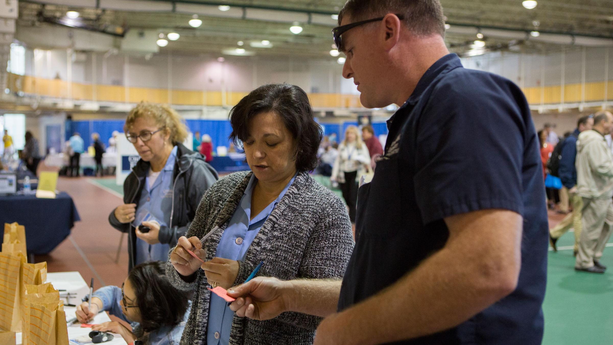Employees place raffle tickets in to bags during benefits fair